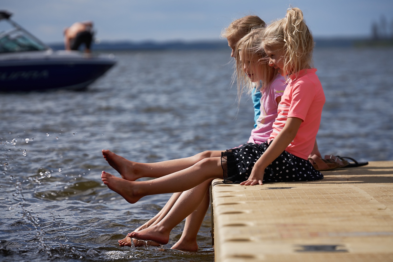 Children sitting on a dock by the lake