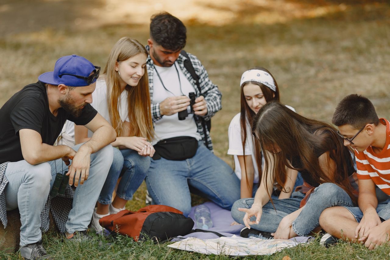 Family group sitting outdoors with a map while planning an adventure